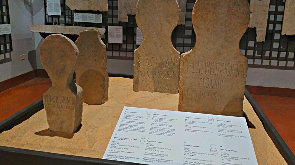 Display in Naples Archaeological Museum, 2 found at Fondo Santilli, 1 from Porta Marina tombs (centre left) and 1 (centre right) from tombs at Herculaneum Gate. June 2017. Photo courtesy of Giuseppe Ciaramella.
According to the information card, cippus on left of centre in photo above -
Marble sepulchral cippus, found 1755, from 42-79AD, inv.3907 (CIL X, 1055) reading –
“Caius Novellius Natalis, cult attendant of aug(ustalis)”.
The deceased is a freedman of the Novelli family, originally from northern Italy.
(“Caio Novellio Natale mag(ister) aug(ustalis)”.
(Il defunto è un liberto della famiglia dei Novellii, originaria dell’Italia settentrionale).
