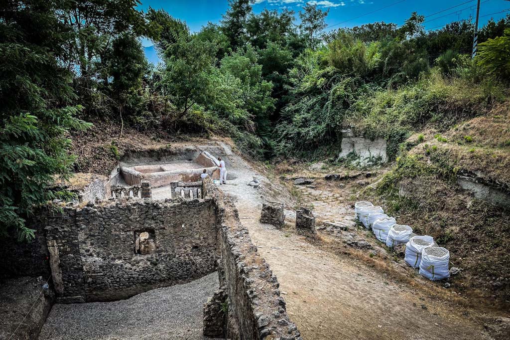 Porta Sarno la tomba di Marcus Venerius Secundio. August 2021. Looking south-east to new tomb opposite road area E.
A hermetically sealed burial chamber can be seen at the front of the tomb. Tomb areas B and A are in the foreground.
Guardando verso sud-est alla nuova tomba di fronte all'area stradale E.
Un ambiente ermeticamente chiuso può essere visto nella parte anteriore della tomba. Le aree tombali B e A sono in primo piano.
Photograph © Parco Archeologico di Pompei.