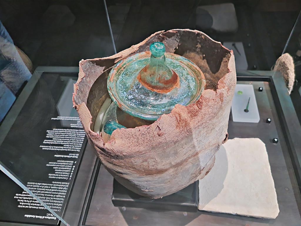 Porta Sarno la tomba di Marcus Venerius Secundio. Tomb of Novia Amabiles. March 2024.
Her cremated remains were preserved in the glass urn.
Photo courtesy of Giuseppe Ciaramella.
On display in exhibition in Palaestra entitled – “L’altra Pompei, vite comuni all’ombra del Vesuvio”. March 2024.