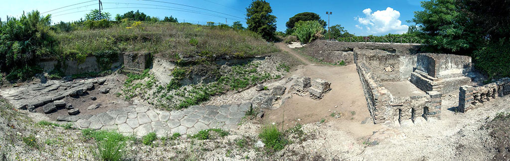 Pompeii Porta Sarno Necropolis. Panoramic view looking north. Tomb enclosures A and B are on the right with area D in front and area H to its left with area J the space between the funeral precincts and the area of the Samnite necropolis behind it.
On the left of the picture are paved area E, area K and paved area E with square area G a funerary monument south of the auxiliary road still partially buried.
The continuation of the Via dell'Abbondanza, area E, the ancient road from the gate, now blocked by the railway, is to the left running west to east.
Photo courtesy Necropolis of Porta Sarno Research Project.