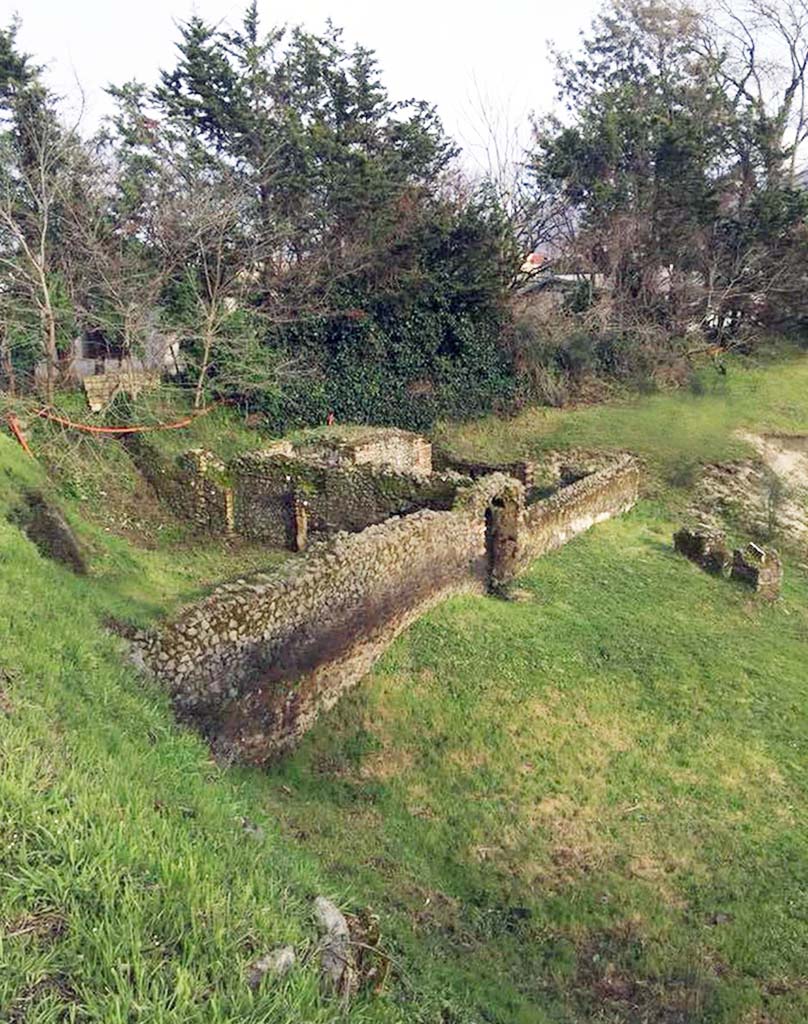 Pompeii Porta Sarno Necropolis. March 2018. Tomb area B, a funerary site with a monument of type “colonnato” is on the left with an arched entrance.
Area A is the funerary site with a monument on a podium behind tomb B, with its entrance in the far end wall.
The grassed Area J, in front of tomb B, is the space between the funeral precincts and the area of the Samnite necropolis.
The separate stones on the far right are the area H, the Praetorian tombs area.