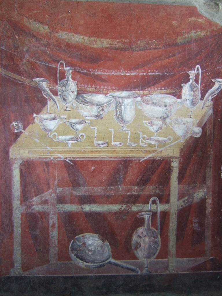 VGJ Pompeii. May 2006. Inner side of north wall of tomb. Painting of the silver flasks, cups, bowls, dishes, ladles used at the funeral feast. These are on a yellow table with a dark red background.