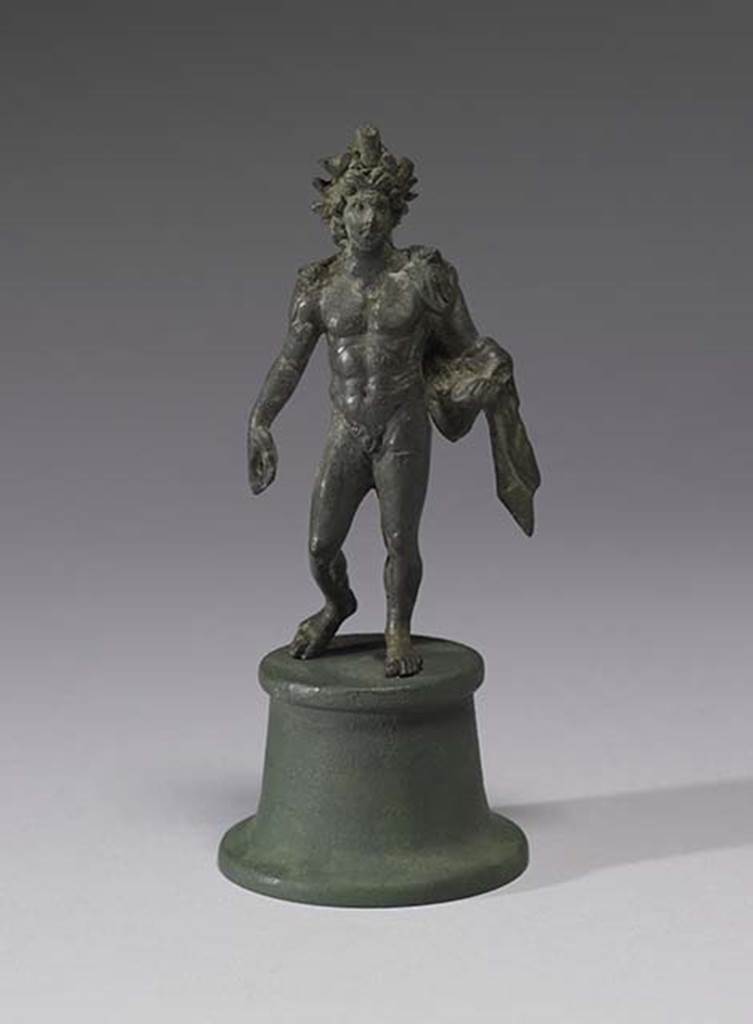 Boscoreale, Villa rustica in fondo D’Acunzo. Room 12, lararium.
Bronze statuette of Alexander Helios, 0.13m high, front view.
A beautiful smiling Helios, he is portrayed nude, with a radiate crown upon his head.
He wears a light veil falling from his shoulders and wrapping around his left forearm.
The left hand (with globe) was missing.
A lorum (leather strap or thong) would have perhaps been the attribute carried downwards in the right hand.
Photo courtesy of The Walters Art Museum, Baltimore. Inventory number 54.2290.
http://thewalters.org/
Creative Commons Attribution-ShareAlike 3.0 Unported Licence