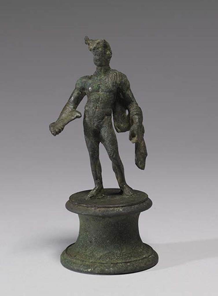 Boscoreale, Villa rustica in fondo D’Acunzo. Room 12, lararium.
According the The Walters Art Museum, this is a bronze statuette of Mercury, front view.
According to Della Corte, this statuette seemed to represent a faun, (0.12 high) naked except for a goat skin between the left shoulder and corresponding elbow.
He has what may be a syrinx? (pan-pipe) held lowered in his right hand.
Upon his head were two projections on the sides of the forehead, apparently horns, but they were seriously damaged.
See Notizie degli Scavi di Antichità, 1921, p. 441. According to Stefani, the different. and more plausible interpretation proposed by others is an image of Mercury.
See Stefani G., 2000. In Sylva Mala, Bollettino del Centro Studi Archeologici di Boscoreale, Boscotrecase e Trecase XII, p. 11-16 and note 44.
Photo courtesy of The Walters Art Museum, Baltimore. Inventory number 54.748.
http://thewalters.org/
Creative Commons Attribution-ShareAlike 3.0 Unported Licence