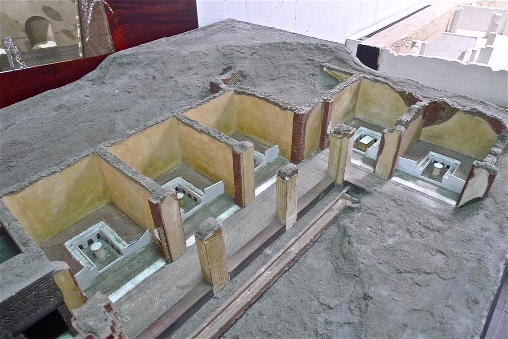 Complesso dei triclini in località Moregine a Pompei. July 2010. Earlier model with triclinium D and triclinium E shown at far end.
Triclinium D is shown with a rectangular table whereas all the others have round tables.
Part of the more recent December 2000 model can be seen in the background.
Photo courtesy of Michael Binns.