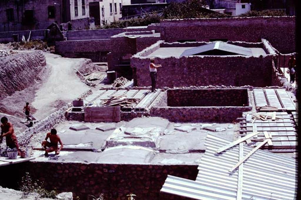 Oplontis, 1977. Reconstruction of the villa, looking south. The two figures on the left are on the roof of room 74. The square hole in the roof is for room 70, a small raised courtyard garden. Photo by Stanley A. Jashemski.
Source: The Wilhelmina and Stanley A. Jashemski archive in the University of Maryland Library, Special Collections (See collection page) and made available under the Creative Commons Attribution-Non Commercial License v.4. See Licence and use details. J77f0119