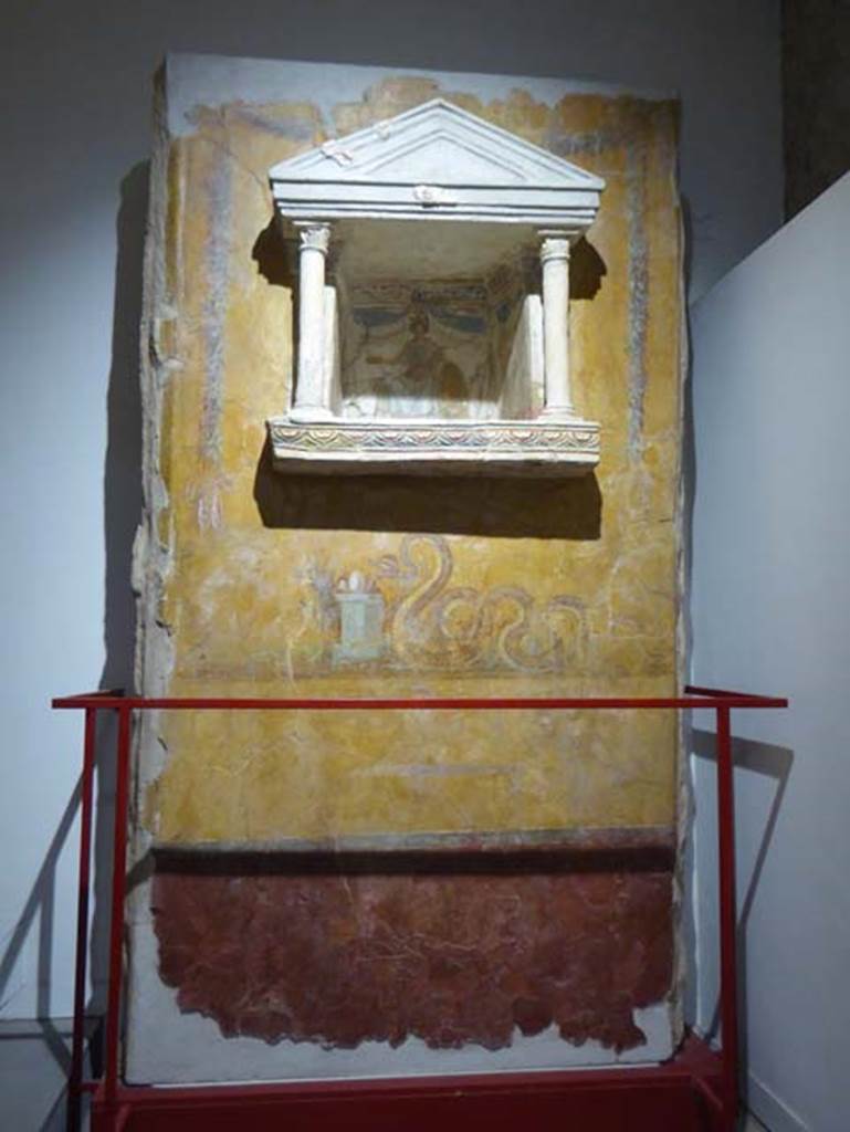 Gragnano, Villa rustica in Località Carmiano, Villa A. June 2017. Aedicula lararium.
From dividing pilaster between kitchen room 4 and room 2.
Stabiae Antiquarium, inventory number 63688.
Photo courtesy of Michael Binns.
Lararium with niche and painting of serpent underneath.
The lararium had a triangular pediment supported by two Corinthian columns.
The painting at the rear showed an enthroned Minerva with breastplate, helmet, shield, lance in the left hand and gilded/golden plate in the right.
Underneath the lararium, a painted serpent was found, moving to the right towards an altar on which was deposited the offerings.
See Fröhlich, T., 1991. Lararien und Fassadenbilder in den Vesuvstädten. Mainz: von Zabern, p. 303, L122, Taf. 15,1.