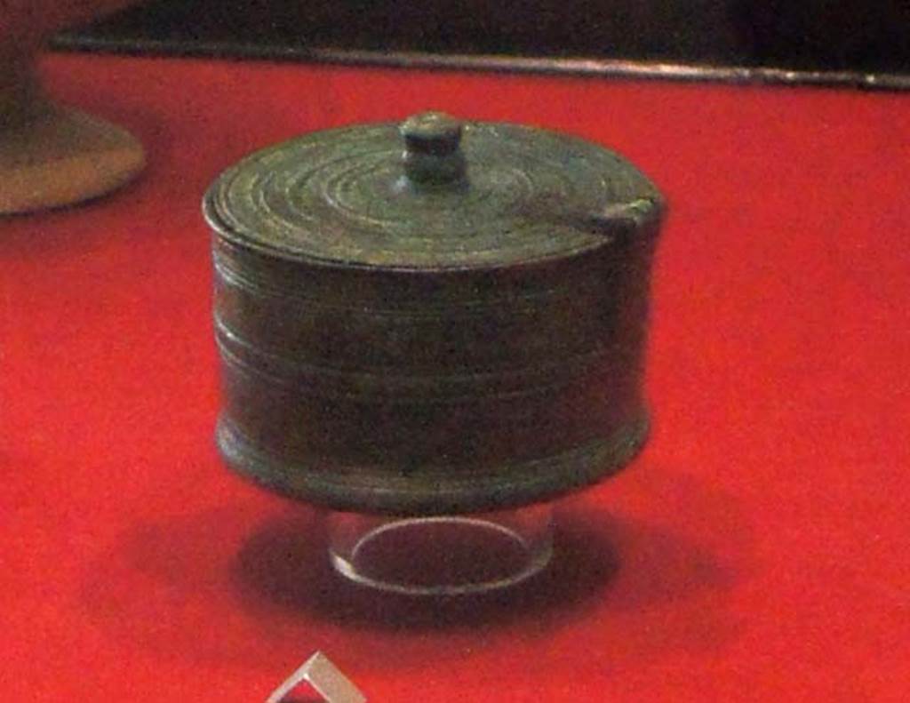 Gragnano, Villa rustica in Località Carmiano, Villa A. Room 9.
Cylindrical bronze pyx (small round lidded box) with hinged lid and decorated with incised parallel lines.
Stabiae Antiquarium, inventory number 63528.
Detail from photo courtesy of Margaret Hicks.