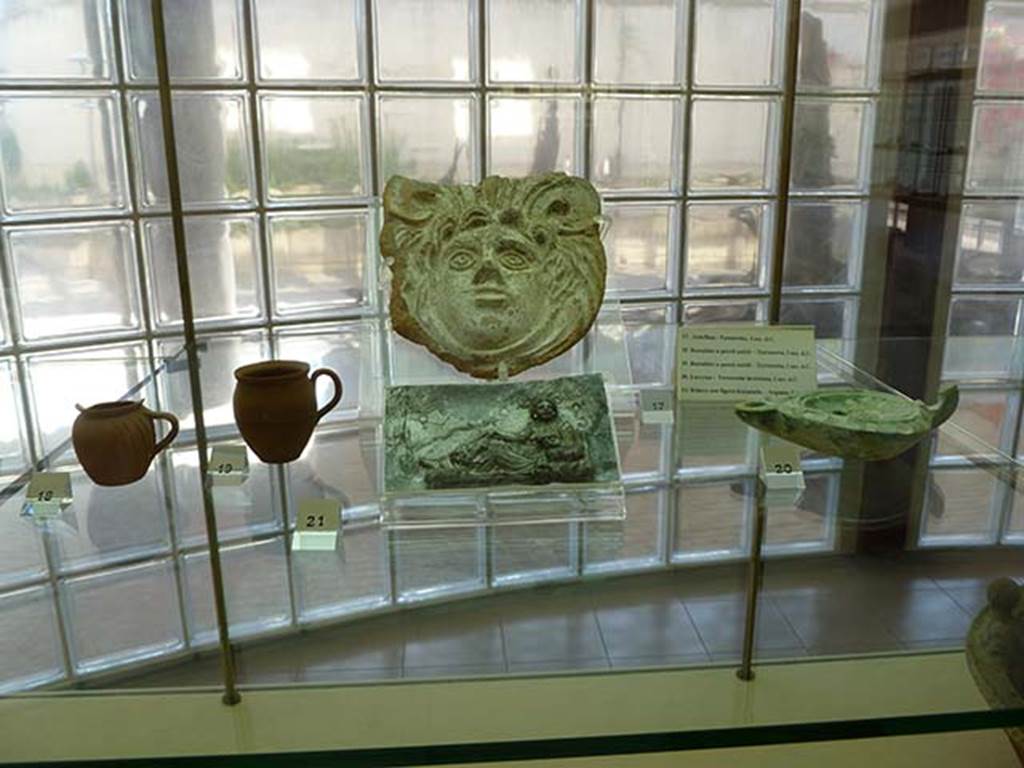 Boscoreale, Villa rustica in via Casone Grotta, proprietà Risi di Prisco.
Finds from villa, from right to left.
18. Thin-walled tankard or jug
19. Thin-walled tankard or jug
17. Terracotta Antefix
21. Silver relief, with depiction of a female figure relaxing
20. Glazed terracotta lamp
Now in Boscoreale Antiquarium. Photo courtesy of Michael Binns.