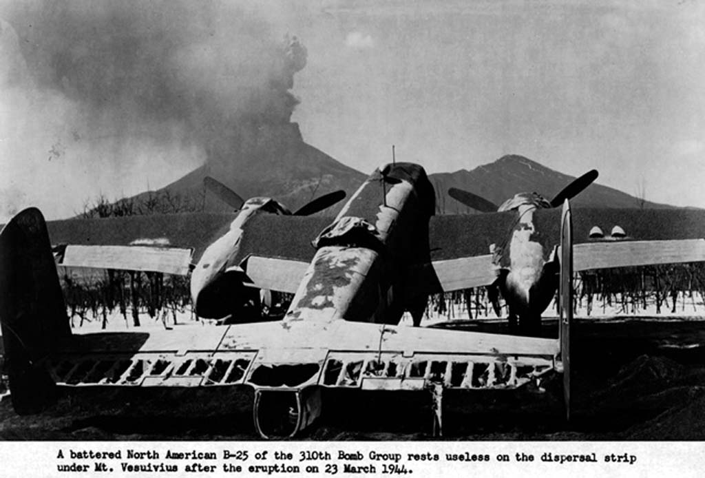 Vesuvius Eruption, 23rd March 1944. An unidentified B-25C Mitchell of the 321st Bombardment group, damaged after the Vesuvius eruption at Pompeii Airfield, Italy (USAF photo).
The volcano erupted, showering nearby airfields with tons of hot volcanic ash and brimstone and severely damaged a significant number of Allied aircraft.
Aside from losing many of its B-25s, the group also suffered significant damage to its maintenance and accommodation facilities.
Pompeii Airfield was a World War II military airfield in Italy, located approximately 1 km south of Terzigno, a few kilometres east of the base of Mount Vesuvius, and approximately 20 km east-southeast of Naples.
The airfield was an all-weather temporary field built by the XII Engineering Command of the United States Army Twelfth Air Force.
The Twelfth's 340th Bombardment Group with their North American B-25 Mitchell medium bombers occupied the airfield on January 2, 1944.
When Mount Vesuvius erupted in March 1944, the B-25s were covered with hot ash that burned the fabric control surfaces, glazed, melted, or cracked the Plexiglas, and even tipped some B-25s onto their tails from the weight of the ash and tephra.
The eruption destroyed the base and nearly all of the 340th's planes. Estimates vary from 70-90 aircraft.
No lives were lost at Pompeii Airfield and the only casualties in the 340th were a sprained wrist and a few cuts, but the effects of the volcano on the aircraft proved insurmountable despite a major effort by the 12th Air Force to repair and salvage the damaged planes.
The US war effort over Italy was postponed or stopped until the aircraft could be repaired or replaced.
Pompeii airfield was dismantled and the 340th relocated to Paestum Airfield on March 23, 1944.