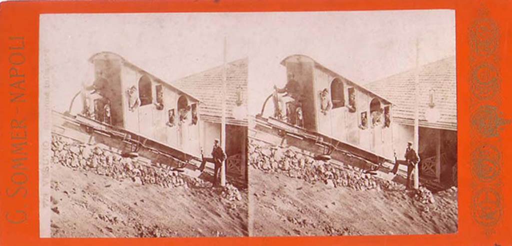 Vesuvius Funicular railway at the lower station, 1880-1889. One of the two original 1880 cars named Etna and Vesuvio which seated 8 people.
There was a longitudinal wooden sleeper on the top of which was carried a single rail.
The cars had a double flanged wheel at each end which ran on this rail.
In addition, there were two angled rails, one fixed to each side of the sleeper at its base.
The cars had wheels mounted from their floors which engaged on these side rails and kept the cars upright.
Each track had two continuous cables carried on pulleys which were fixed to each side of the car.
These cars were replaced in 1889 by new cars with 10 seats, also named Etna and Vesuvio, as part of renovations by John Mason Cook.
Stereoview photo by Giorgio Sommer.