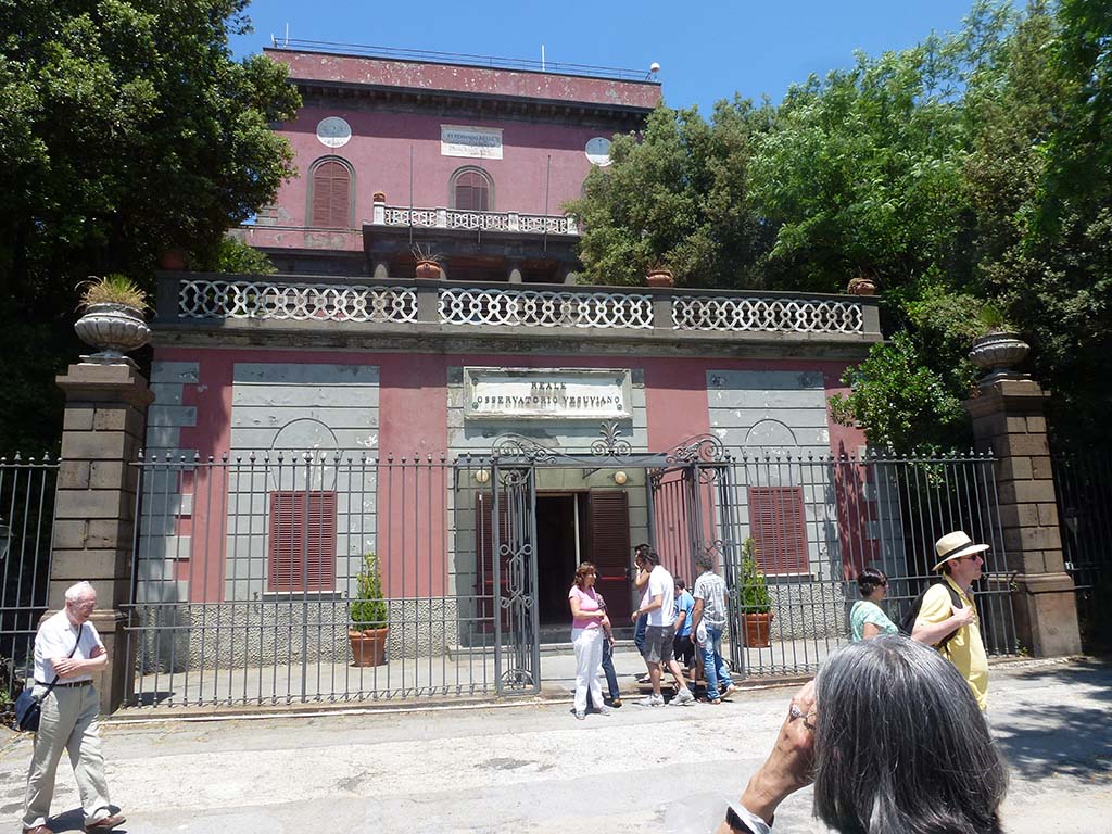 Vesuvius, June 2012. Observatory with plaque above the door: Reale Osservatorio Vesuviano (Royal Vesuvius Observatory).
Photo courtesy of Michael Binns.
The upper plaque at roof level commemorates its founding in 1841, by Ferdinando II of Bourbon, King of The Two Sicilies.
It is the oldest volcanology observatory in the world.
The Vesuvius Observatory is responsible for monitoring of active volcanoes such as Vesuvius, Campi Flegrei and Ischia.
Now it is home to the Naples branch of the Istituto Nazionale di Geofisica e Vulcanologia (INGV), the National Institute of Geophysics and Volcanology.