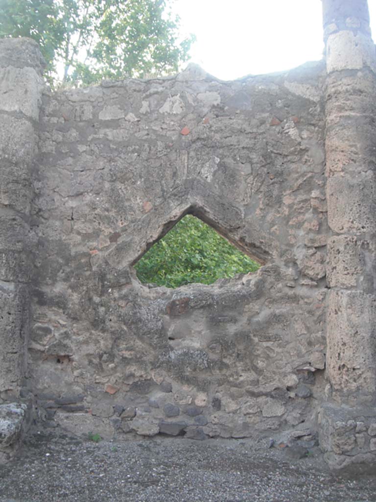 Vicolo dei Soprastanti, Pompeii. May 2011.
Triangular peephole between Doric columns, set into north wall. Photo courtesy of Ivo van der Graaff